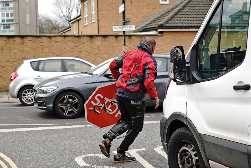 A man running away with a stop sign in his hand