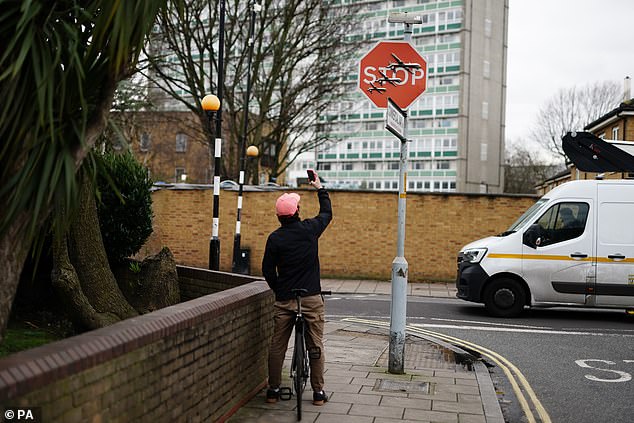 A man on a bike takes a photo of the artwork at the intersection of Southampton Way and Commercial Way in Peckham