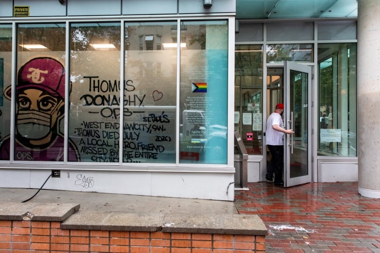A man enters a door with a colourful mural that says 'Thomus Donaghy OPS.'