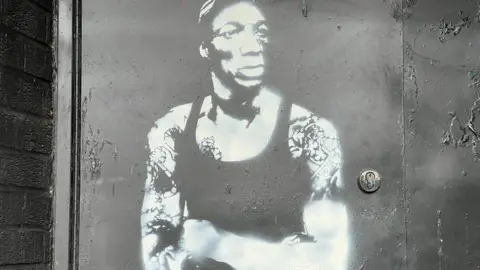 White spray painted mural of Bristol rapper Tricky on a black wall