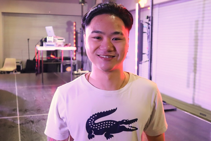 Man smiling at the camera in front of a stage.