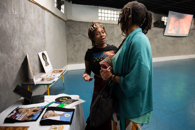Tia Maat of Detroit, center, chats with an attendee about the artwork of her son, Kojo Brooks, during Dilla Family Day at the Alkebu-lan Village on Saturday, Feb. 10, 2024 in Detroit. The event featured roller skating, educational workshops and a pizza lunch.