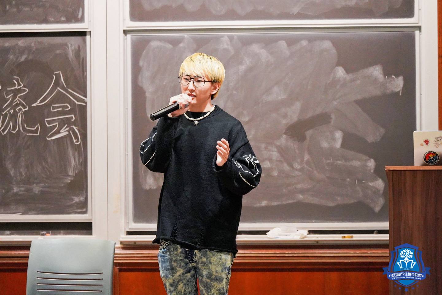 Photo of a person holding a microphone in front of a blackboard