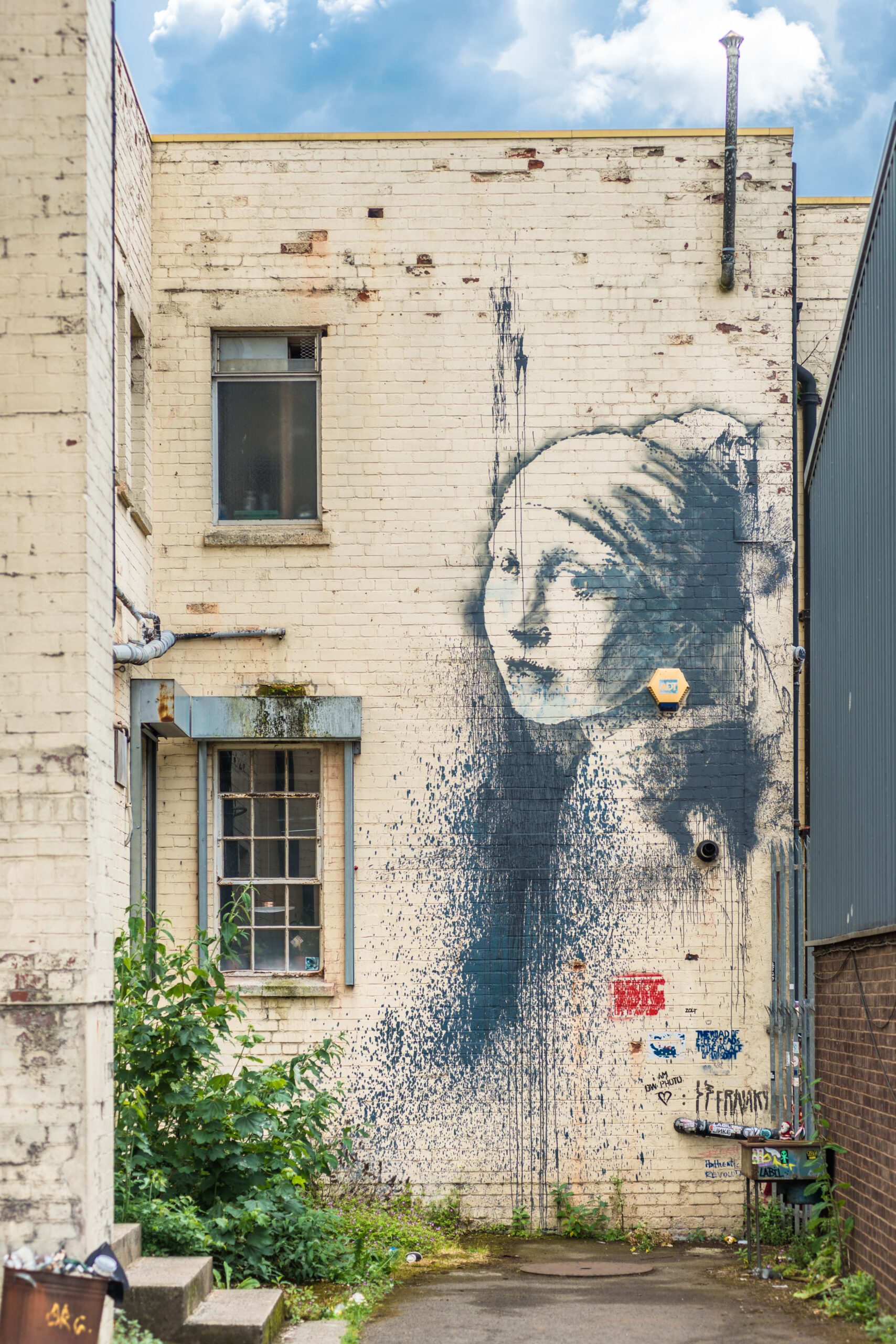 Girl with a Pierced Eardrum, by Banksy on the wall of an alley in Albion Docks, Bristol