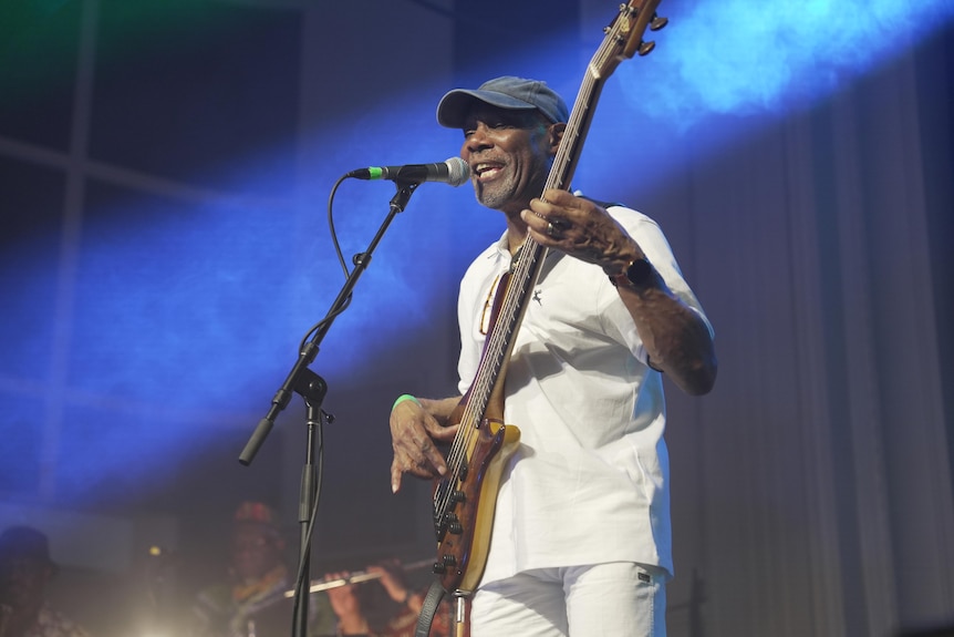 A man playing guitar and singing on stage.