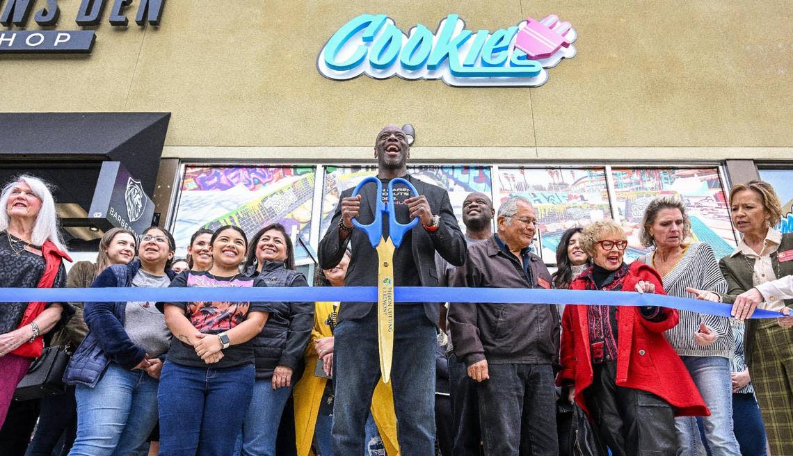 Kevin Jordan, center, franchise owner of Cookie Plug, gets ready to cut a ribbon for the company’s new store at Fresno State’s Campus Pointe shopping center during its event.