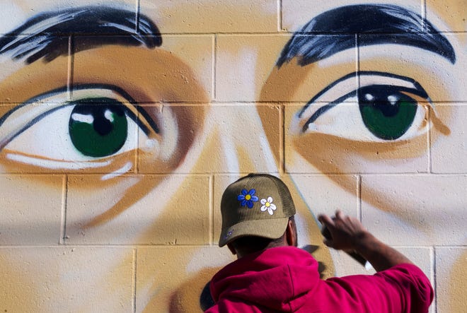 Indianapolis street artist Kwazar Martin blends facial shadows Monday, March 11, 2024, while putting the finishing touches on his most recent work, a graffiti mural of Iowa Hawkeyes basketball player Caitlin Clark.