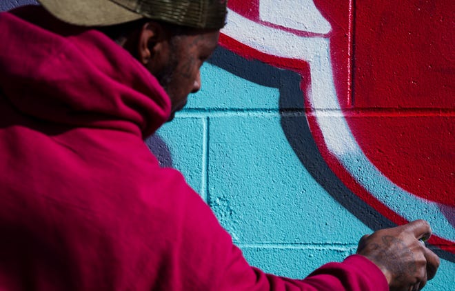 Indianapolis street artist Kwazar Martin lines the Indiana Fever logo Monday, March 11, 2024, as he puts the finishing touches on his most recent work, a graffiti mural of Iowa Hawkeyes basketball player Caitlin Clark.