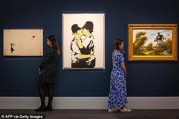 Prints of three of Banksy's works are seen above at Sotheby's in February last year. Centre is  Kissing Coppers, next to Girl With Balloon and Vandalised Oils (Choppers)