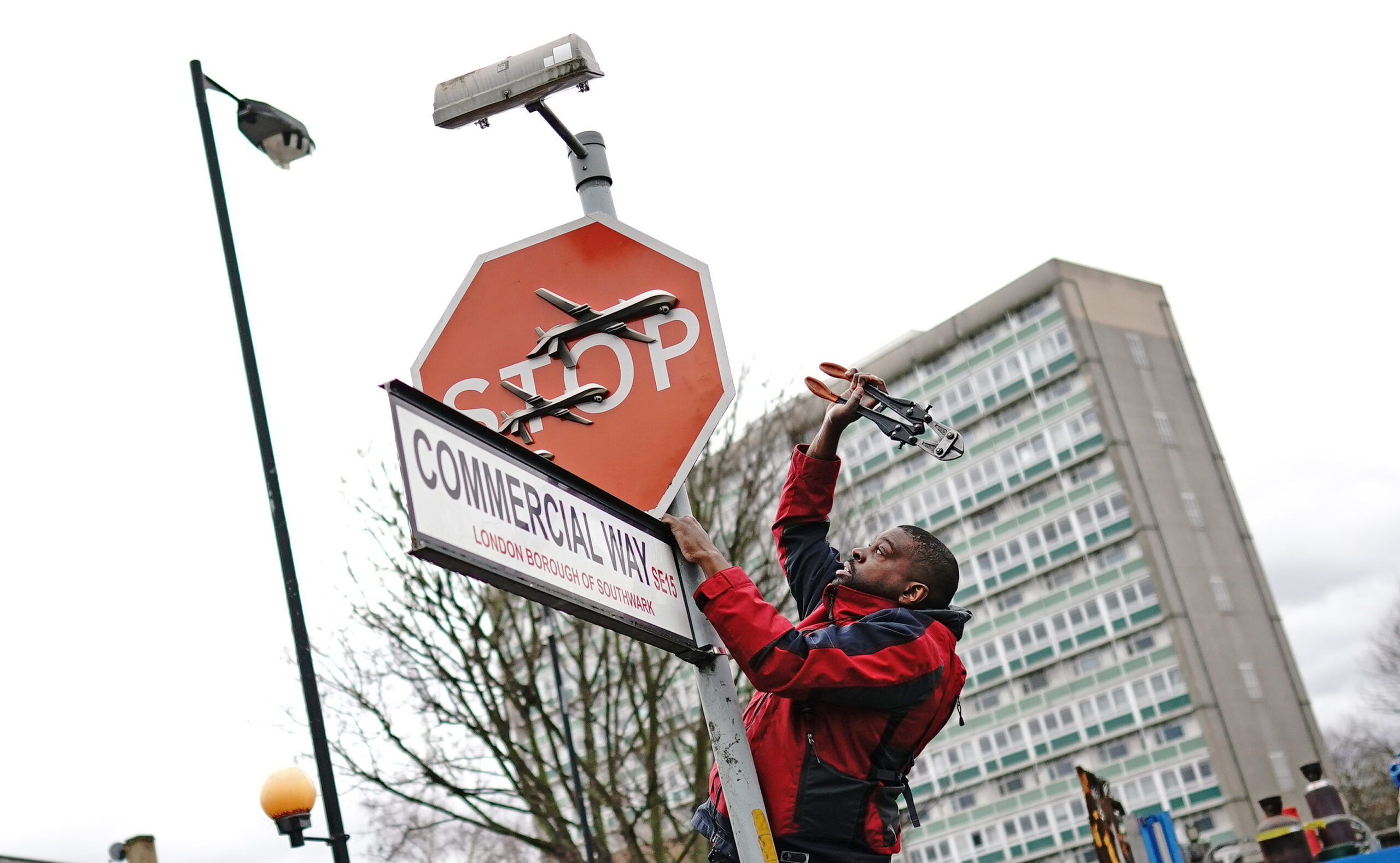 Man holds up bolt cutters to red stop sign