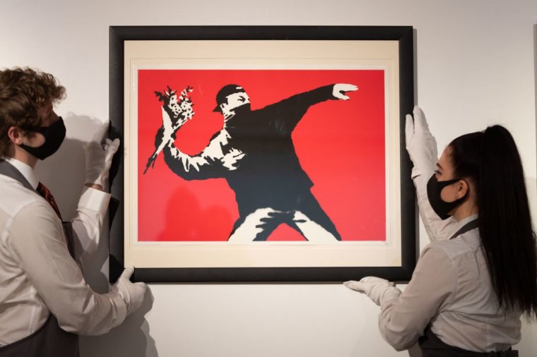 LONDON, ENGLAND - MARCH 26: Love is in the Air by Banksy is displayed during preparations ahead of online sales at Christies Auction House on March 26, 2021 in London, England. The sale includes