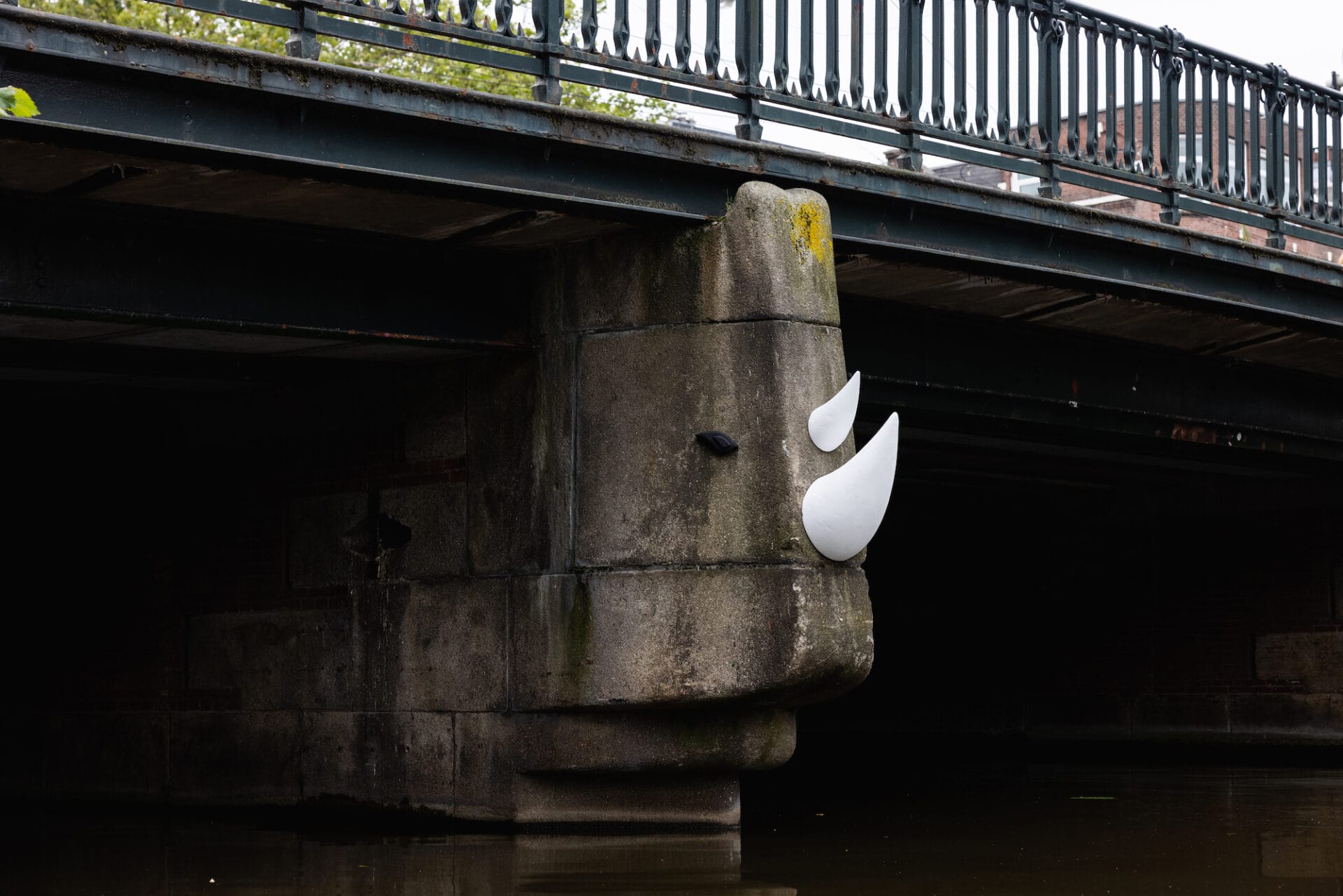 A street art intervention on a bridge column with eyes and two white horns to make it look like a rhino.