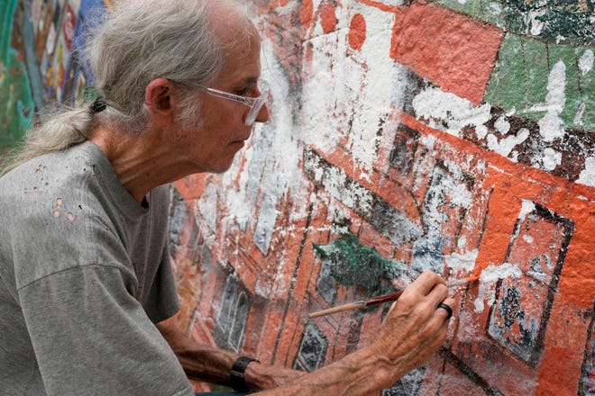Tom Bauman helps restore the “Austintatious” mural he originally painted with Kerry Awn and Rick Turner as University of Texas art students in 1973, on the north wall of the University Co-Op Monday April 1, 2024.