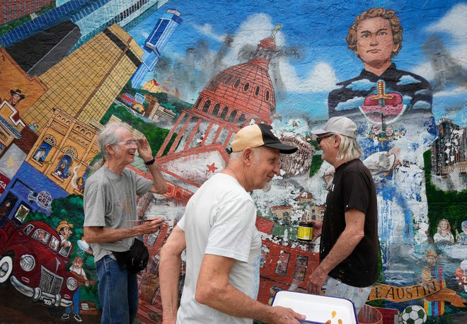 Tom Bauman, left to right, Rick Turner and Kerry Awn restore their “Austintatious” mural they originally painted as University of Texas art students in 1973, on the north wall of the University Co-Op Monday April 1, 2024.