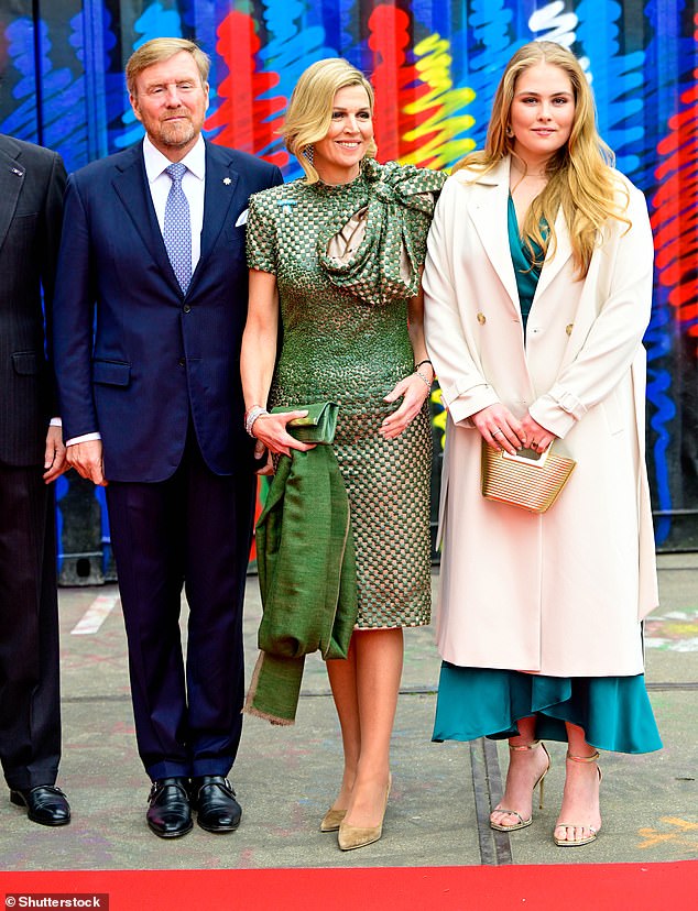 Looking smart in a navy suit, King Willem-Alexander stands with wife Queen Maxima and their daughter Princess Amalia