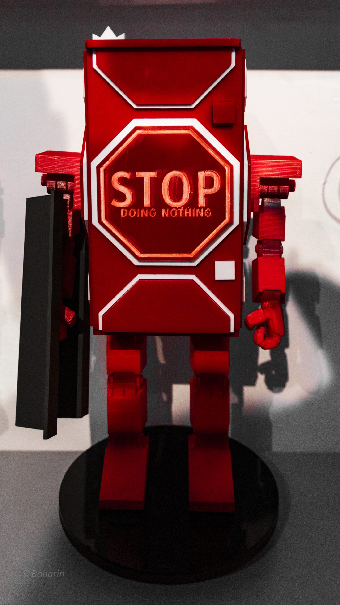 Red robot sculpture with a stop sign that says 