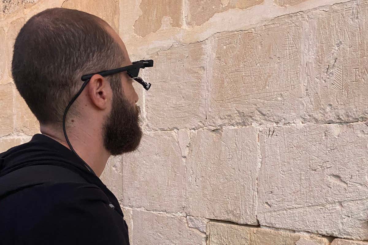 Matthew Attard with an eye-tracking device, tracing ship graffiti at Our Lady of the Visitation Chapel, Wied Qirda - ?ebbu?, Malta, 2021 - Elyse Tonna