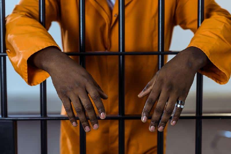 Man behind bars (in jail) - Depositphotos