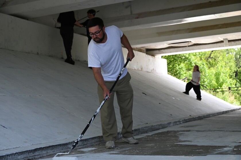 A man painting a bridge.