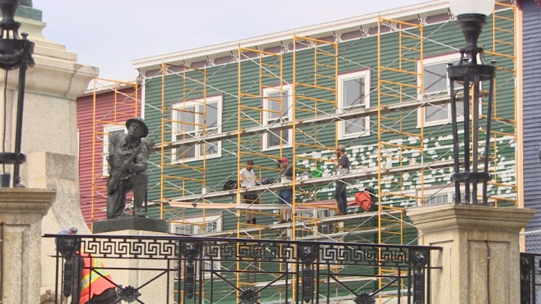 workers on a scaffold, painting a building on Duckworth Street in St. John's.