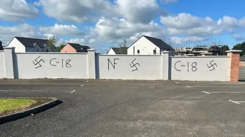 BBC The perimeter wall of a new estate was daubed with swastikas and Combat 18 signs