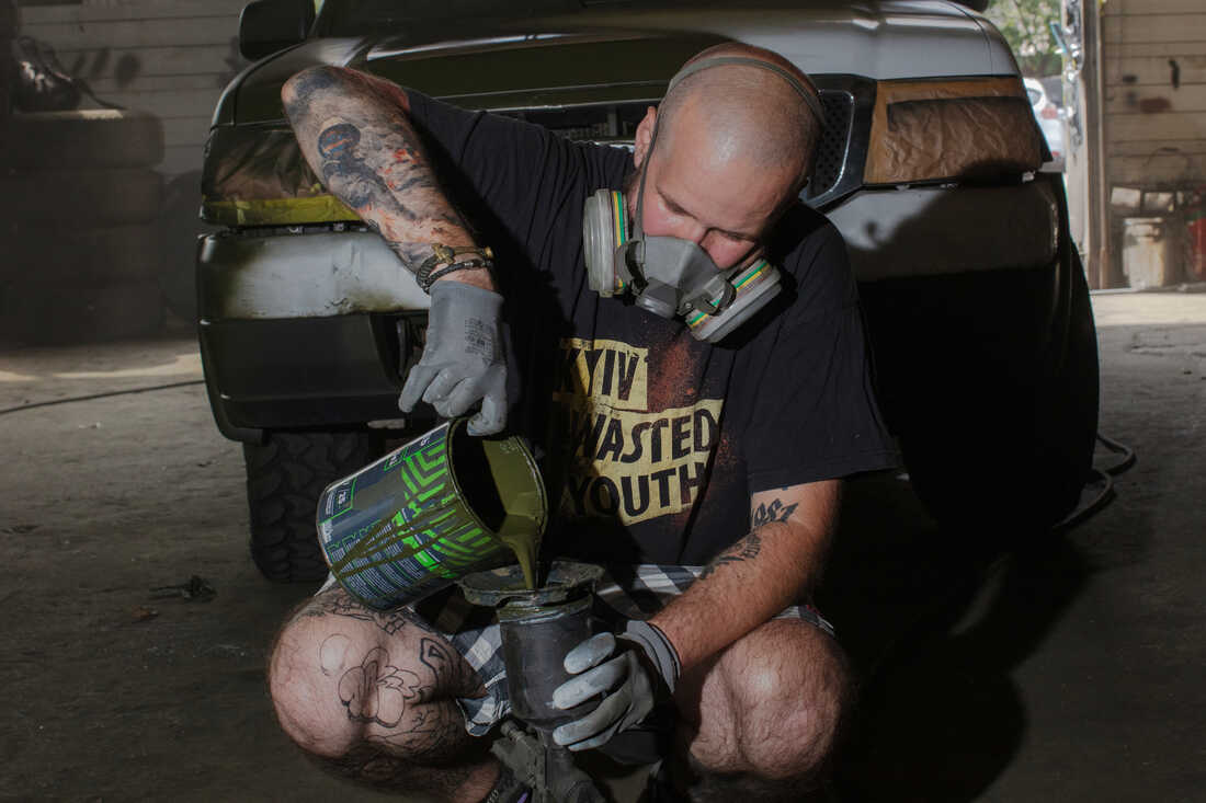 Neak, a 43-year-old Ukrainian graffiti artist, mixes green paint at a workshop in Kyiv, Ukraine. His ETC graffiti crew works to camouflage cars to be sent east to the front line of the war with Russia.