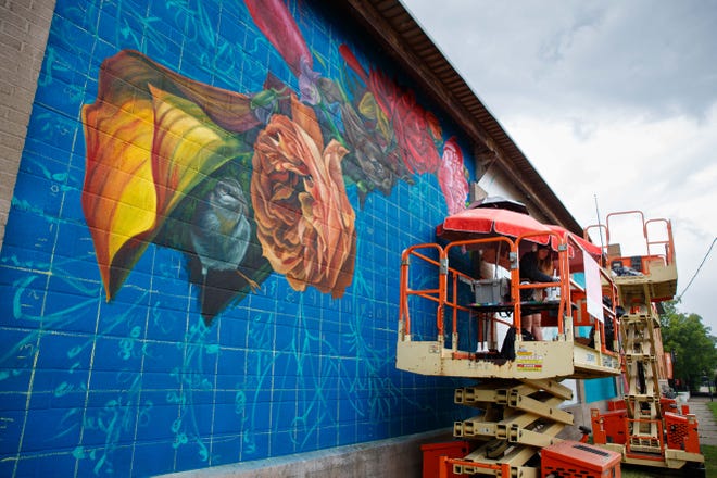 Nico Cathcart of Toronto dips her brush into paint for her mural on the side of the ZStone Creations building at 711 South Main Street during Mural Mania on Friday, July 5, 2024, in South Bend. This year marks South Bend's third Mural Mania where artists from around the world paint murals across the city at the same time.