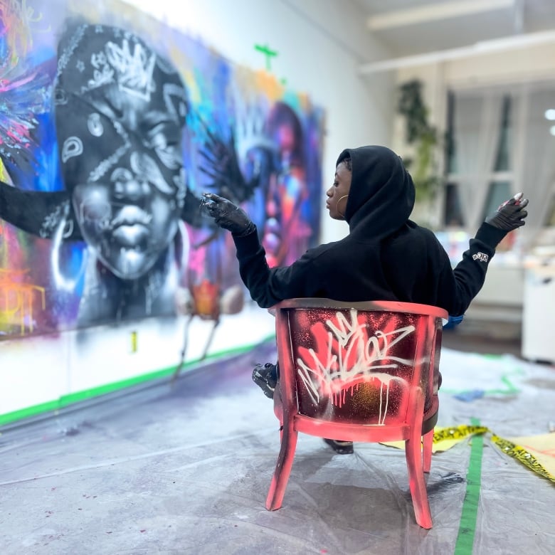 An artist poses for a photo in front of one of her murals