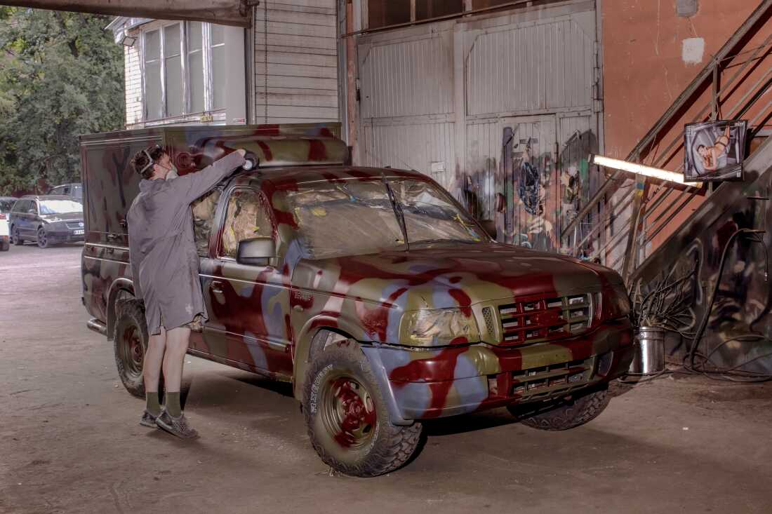 A painter adds dark red spots to a truck to camouflage with the reddish dirt and mud often found in Ukraine's east and south.