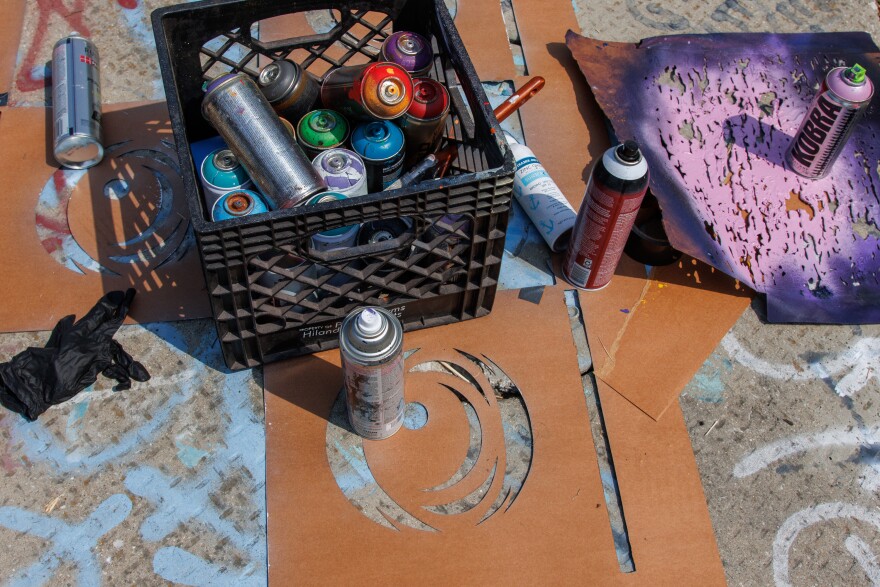 Peat Eyez spray paint and stencils sit out in the sun along the Mississippi River on Friday, August 30, 2024.