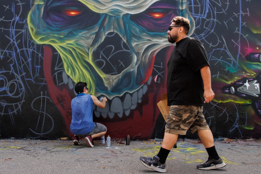 Carlos Barboza, 35, from Oklahoma City, spray paints the teeth of the skull along the Mississippi River on Friday, August 30, 2024. This is the first time Barboza is contributing and in St. Louis.