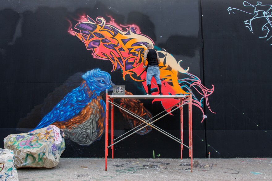 Matt Minetta, 44, from Arizona, spray paints his “SAD” piece along the Mississippi River on Friday, August 30, 2024.