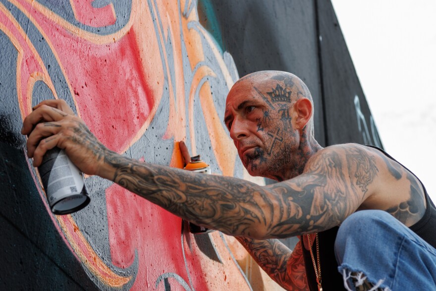 Matt Minetta, 44, from Arizona, spray paints his “SAD” piece along the Mississippi River on Friday, August 30, 2024.