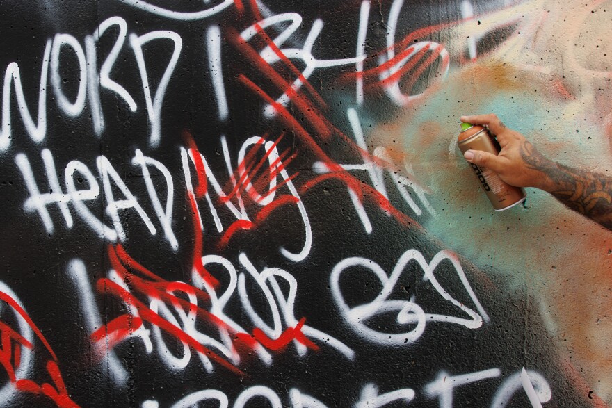 Eddie Rivera, 50, of Key West, Florida, spray paints over his outline along the Mississippi River on Friday, August 30, 2024.