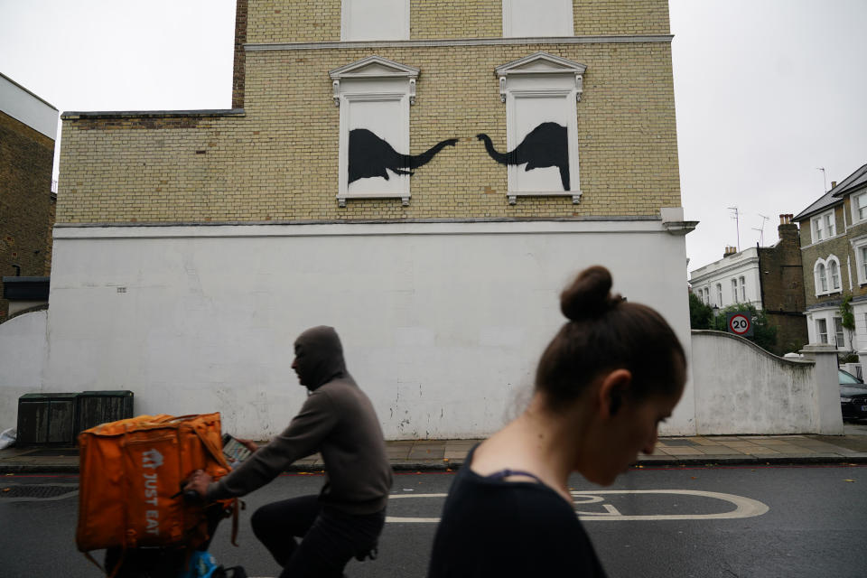 People pass a new artwork depicting two elephants poking their heads out of blocked out windows unveiled by Banksy on the side of a building at the junction of Edith Grove and Edith Terrace, in Chelsea, south west London. Picture date: Tuesday August 6, 2024. (Photo by Yui Mok/PA Images via Getty Images)