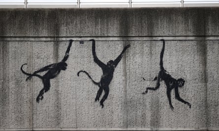 A mural of three monkey silhouettes appearing to swing by hands and tail across a horizontal line in a concrete bridge