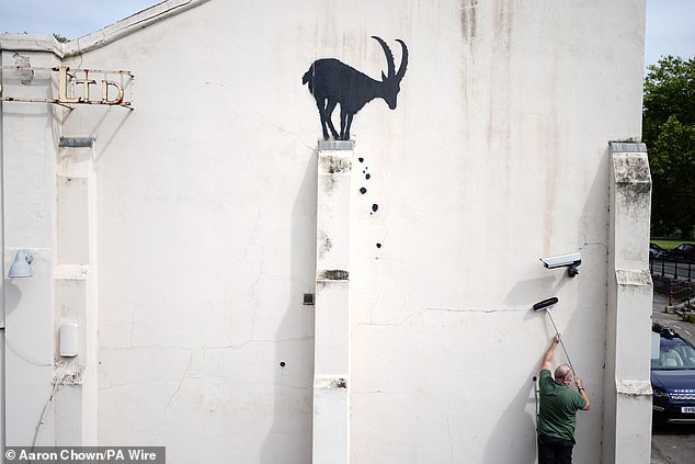 Employees move a CCTV camera back to its original position today after Banksy moved it