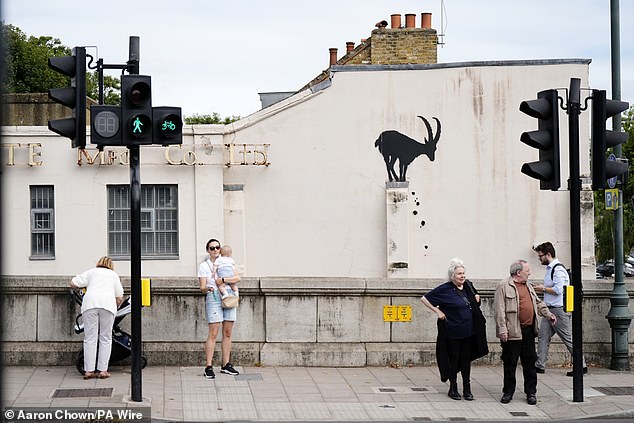 People look at the the new Banksy piece of artwork near Kew Bridge of a goat on a wall today