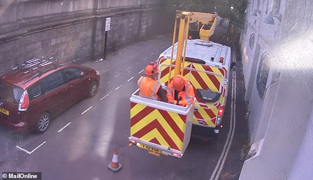 Two men are seen in the back of the cherry picker van in Kew Bridge early yesterday morning