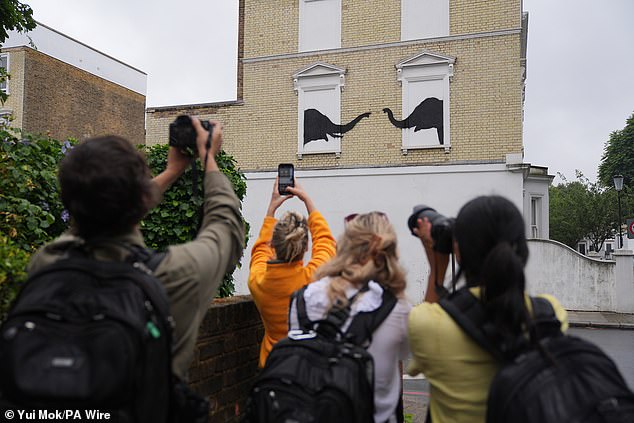 People photograph the new artwork unveiled by Banksy in Chelsea, South West London