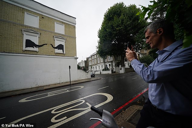 A man stops to look at a new artwork depicting two elephants in Chelsea, South West London