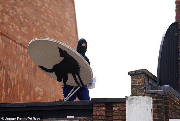 Within hours of its unveiling, a hooded man with a mask was seen holding the satellite dish while standing on top of the building - and the wolf artwork's whereabouts are now unknown