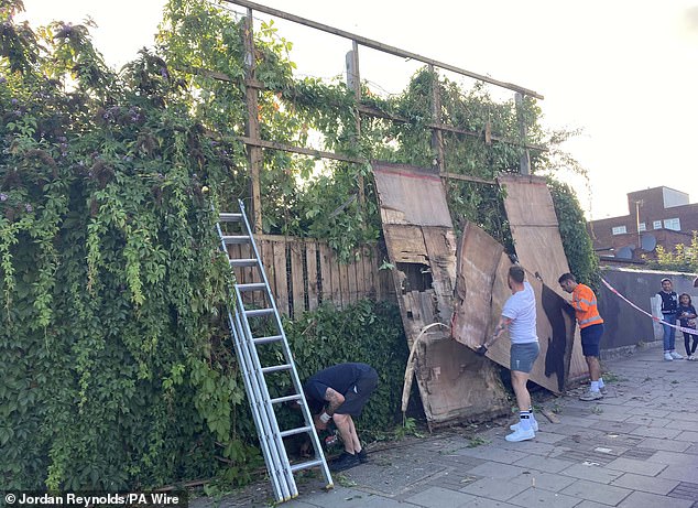 Contractors taking down Banksy's latest artwork - a silhouette of a cat on a billboard in Cricklewood