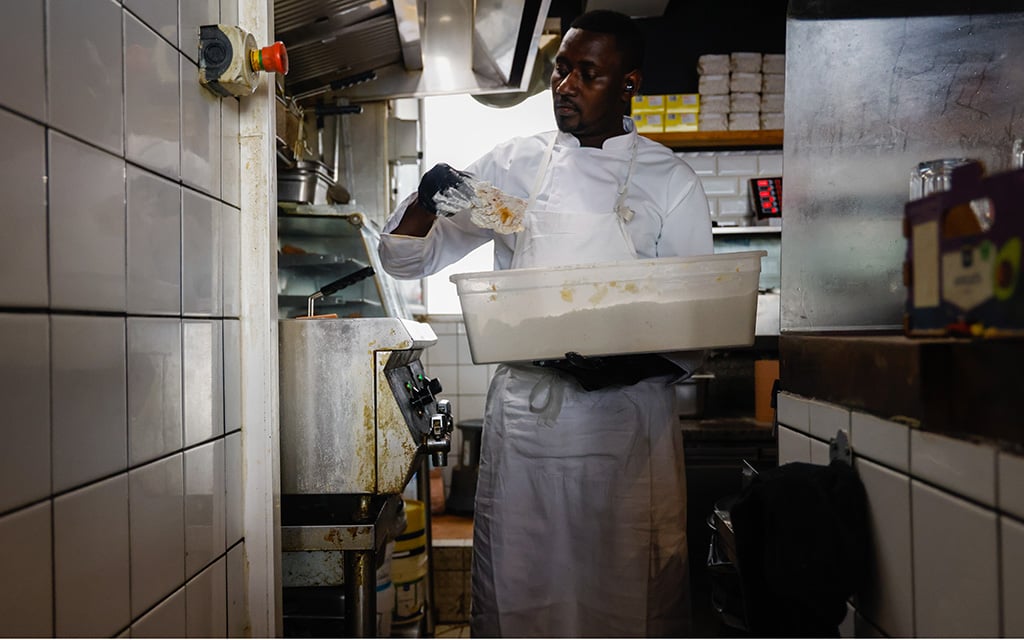 A cook batters and fries chicken in the kitchen of Gumbo Yaya. The restaurant attracts locals but also popular hip hop artists. (Photo by Sydney Lovan/Special for Cronkite News)