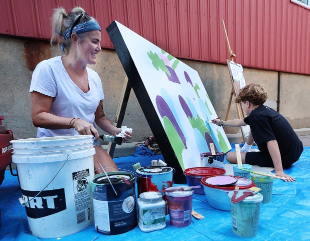 Hutch Wittmer 14, right, gets help from his mom, Ash Wittmer, left, an artist and photographer, as she cleans some brushes for him during Mural Week put on by the Valparaiso Creative Council as artists created murals as part of a goal of making downtown Valpo an arts mecca on Saturday, Aug. 24, 2024. (John Smierciak/for the Post-Tribune)