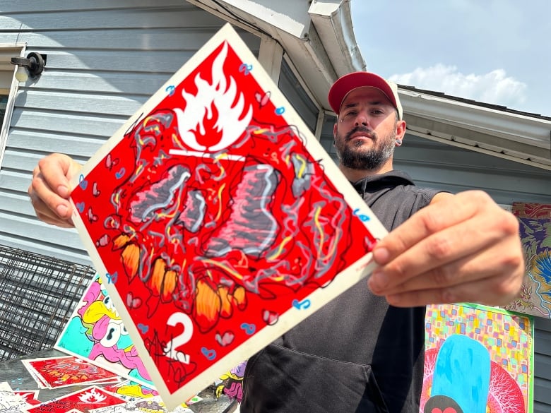 A man holds a piece of street art.