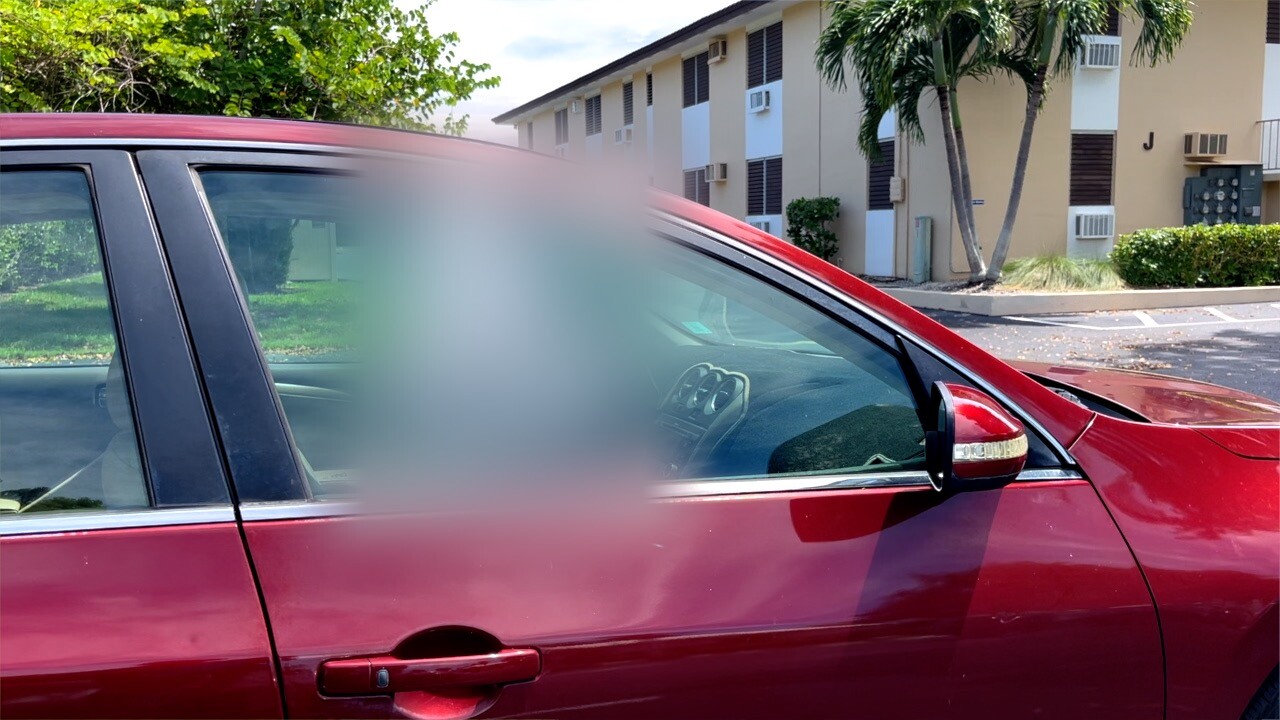 Sedan with graffiti on the passenger side window.