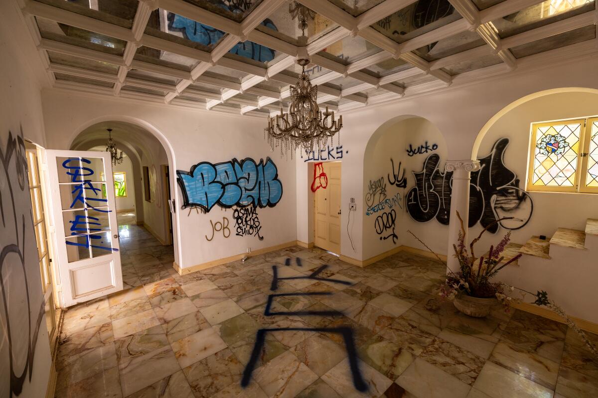 Graffiti covers the inside of a mansion.