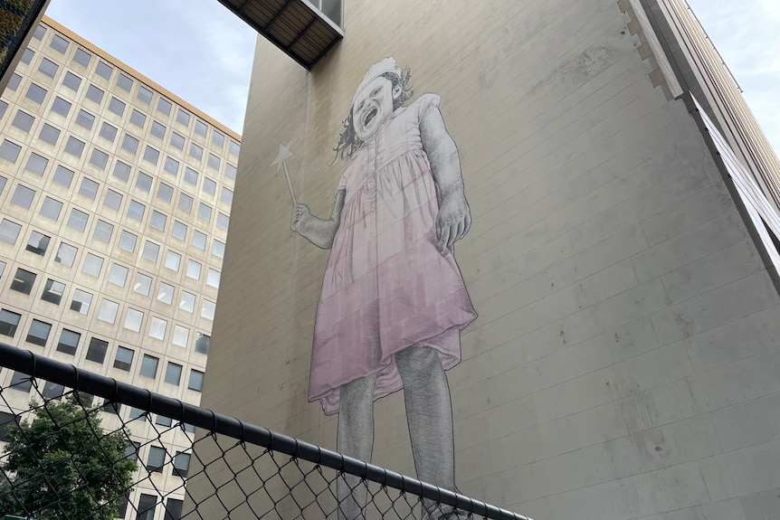 A mural of a young girl on the side of a building