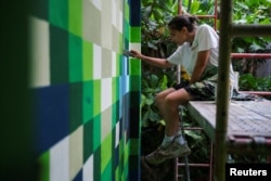 Italian artist Beatrice Vigoni paints a building as part of the Zacamil Project in Mejicanos, El Salvador, Aug. 13, 2024.